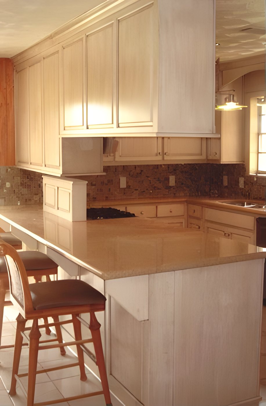 Kitchen with an eating bar, pale cabinets and a mosaic backsplash