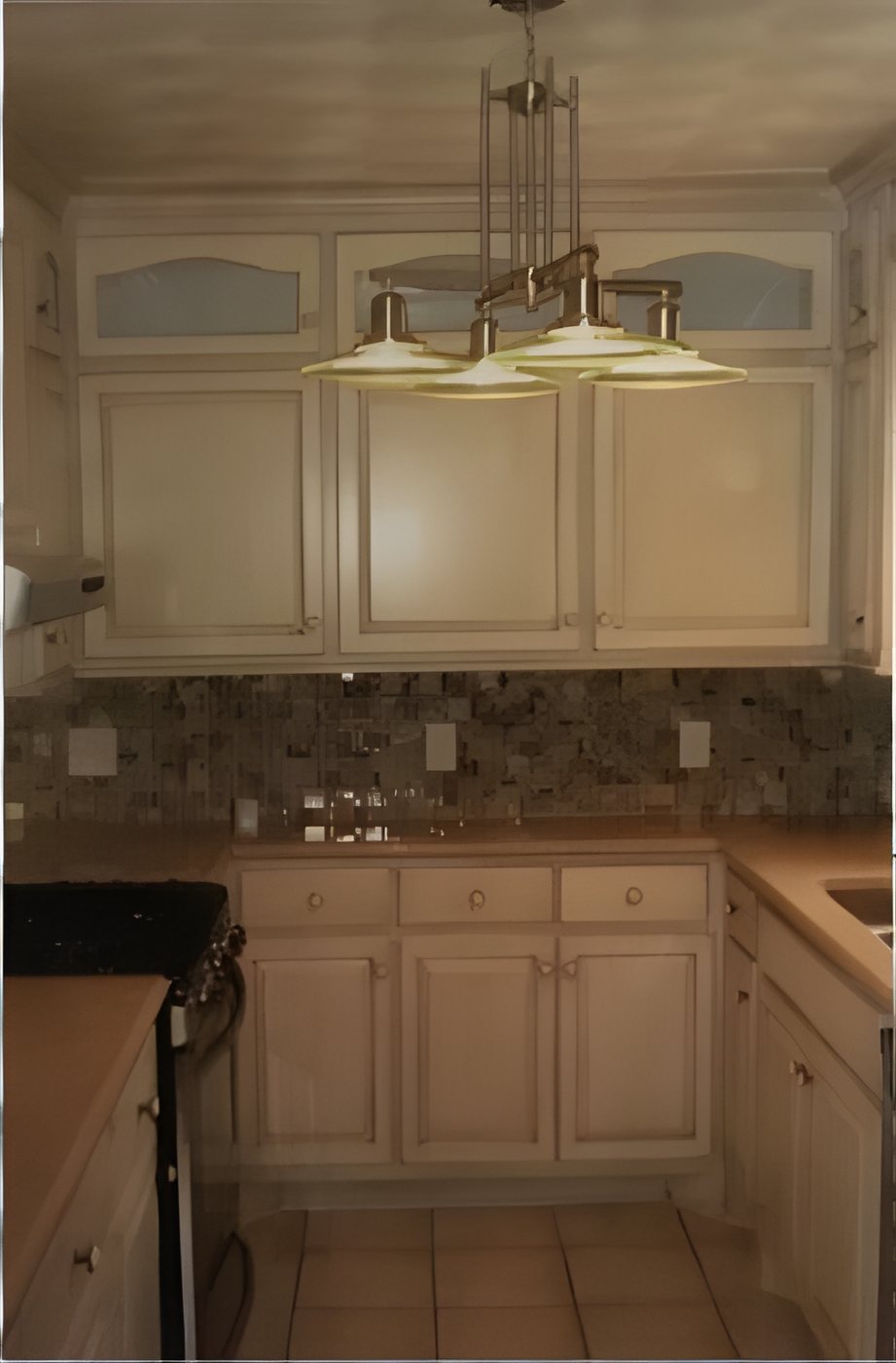 Galley kitchen with cream cabinets, glass upper doors and a pendant light